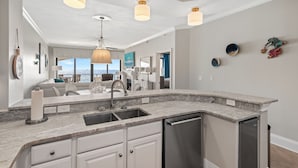 A modern kitchen with a built-in dishwasher, a large island with a sink, and pendant lighting. - Villa Coyaba 306 | Private Beachfront | Includes Daily Beach Setup | Pool (Destin)