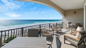 A balcony with a view of the beach and ocean. There are outdoor seating arrangements and a table. - Villa Coyaba 306 | Private Beachfront | Includes Daily Beach Setup | Pool (Destin)
