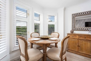 Comedor con una mesa redonda, cuatro sillas, un cuenco decorativo y un mueble de madera con espejo.