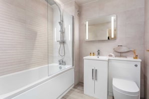 Un baño moderno con bañera, inodoro y tocador con espejo.