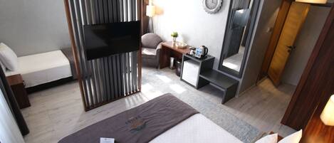 A hotel room with a bed, a desk, a chair, a TV, a mirror, and a wardrobe.