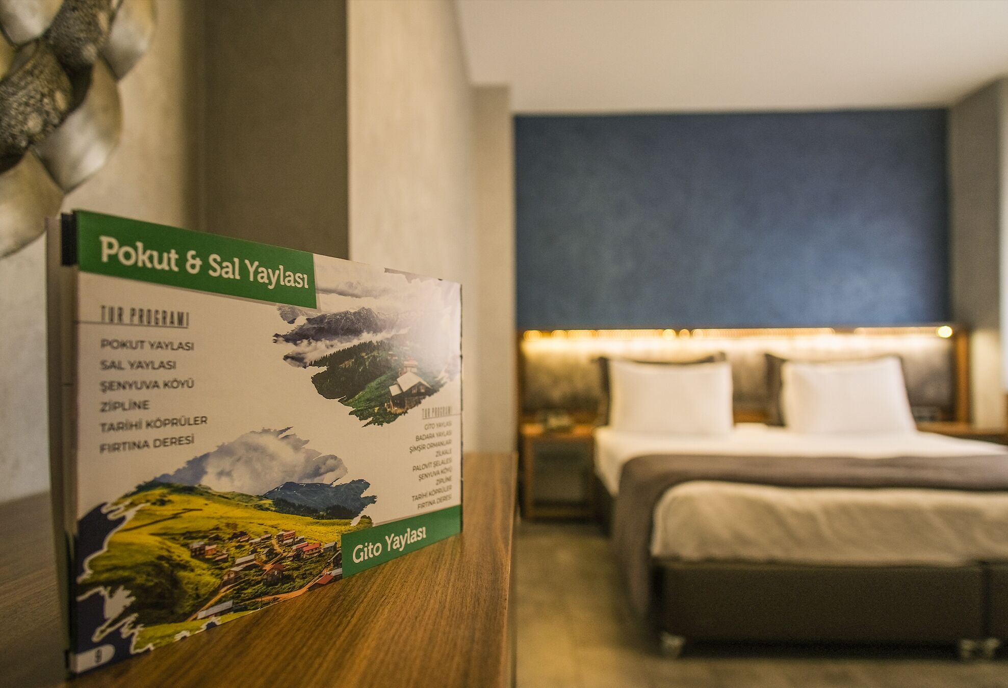 A hotel room with a bed, a nightstand, and a sign about Pokut & Sal Yaylası.