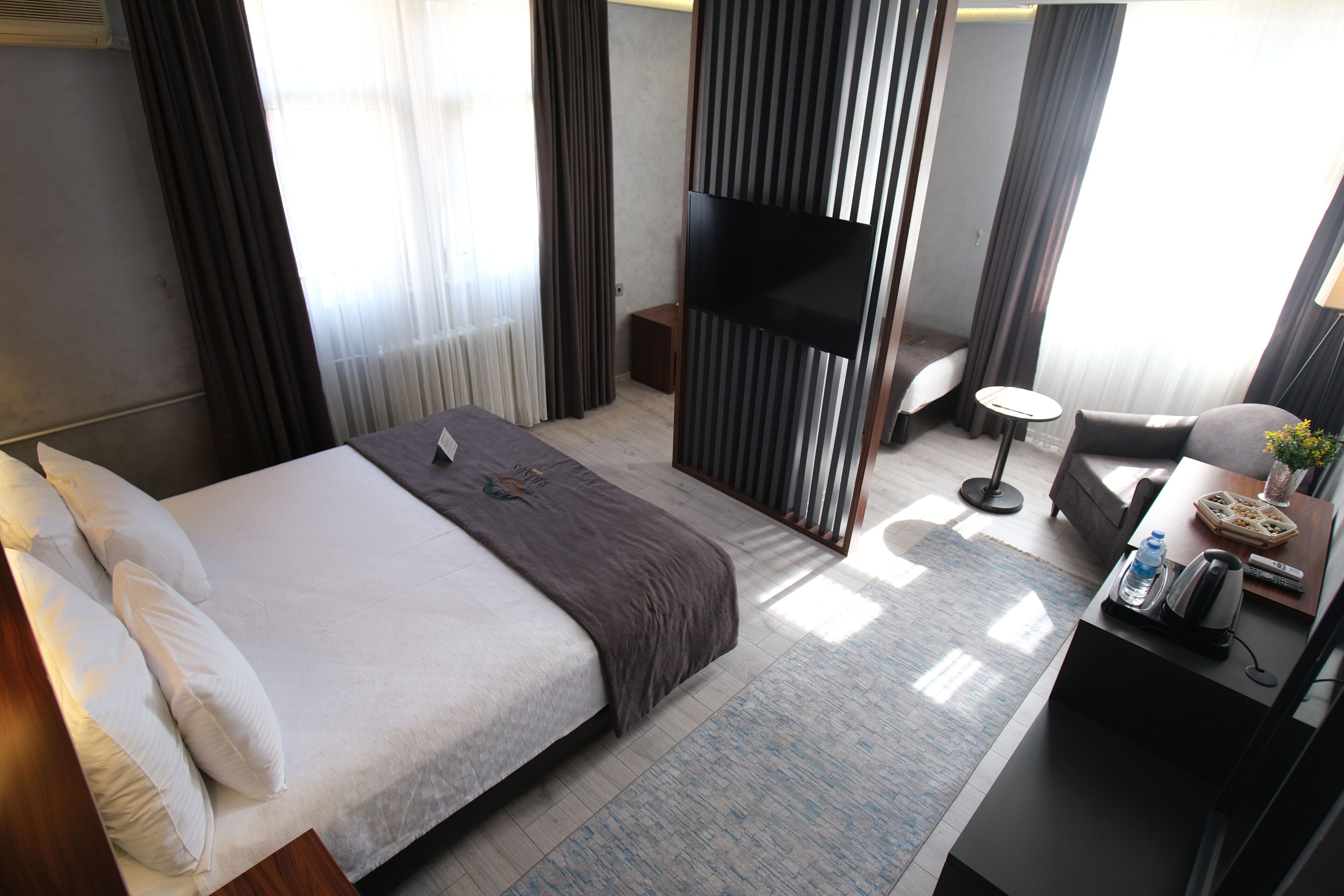 Une chambre d’hôtel avec un lit, une télévision, une petite table avec une bouteille d’eau et une chaise.
