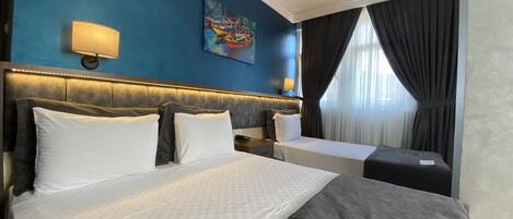 A hotel room with a large bed, two bedside tables, a painting on the wall, and a window with curtains.