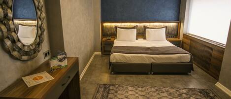 Un dormitorio con cama, mesitas de noche, un espejo y un tapete estampado.