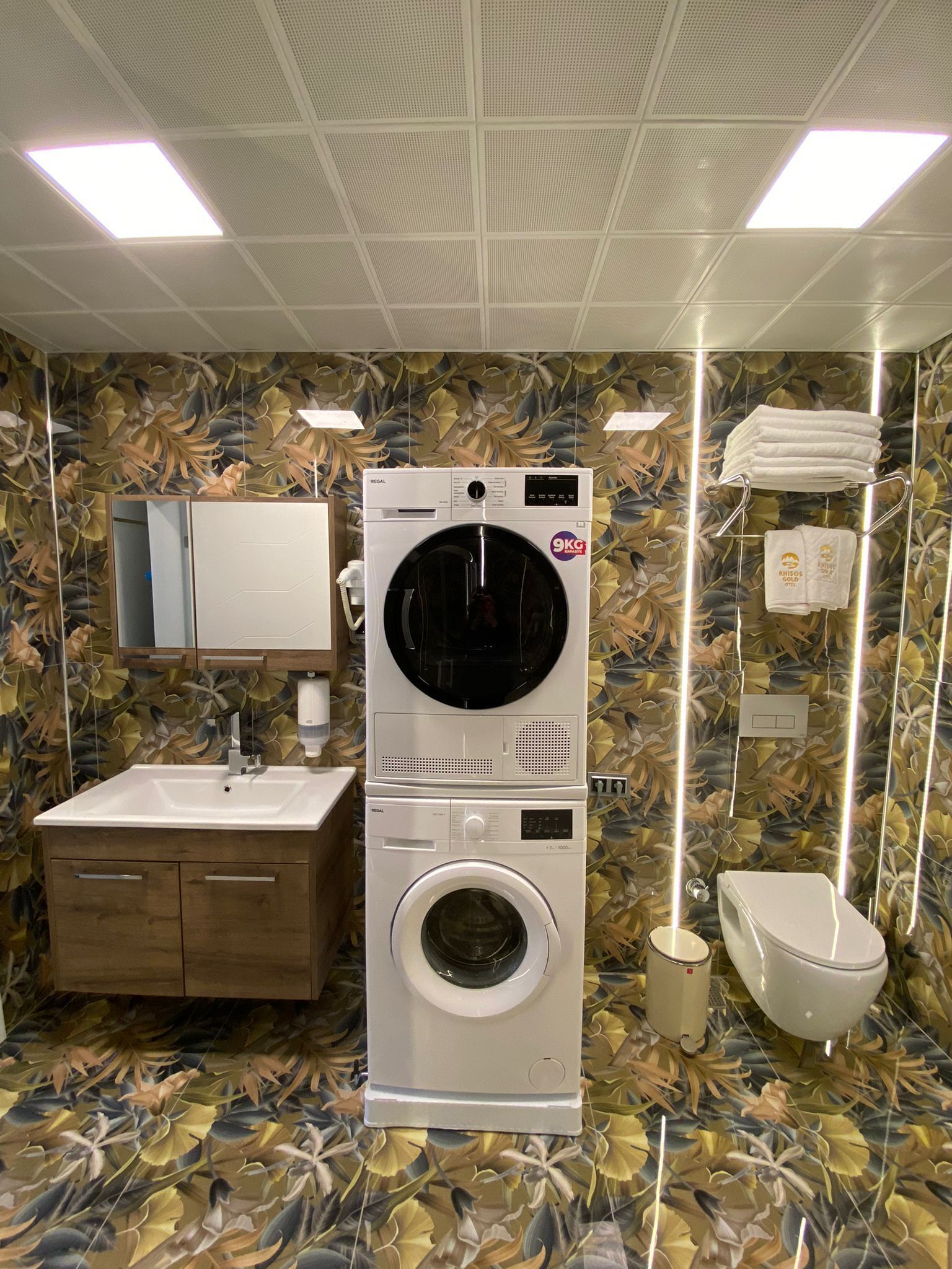 A compact, modern bathroom with a built-in washer and dryer, a wooden vanity, and a toilet.