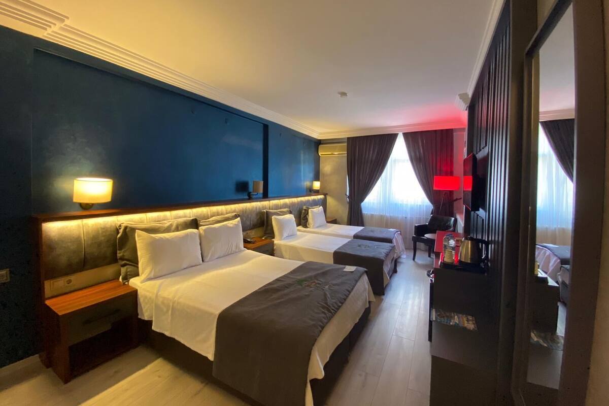A hotel room with two beds, a desk, a chair, a TV, and a large mirror.