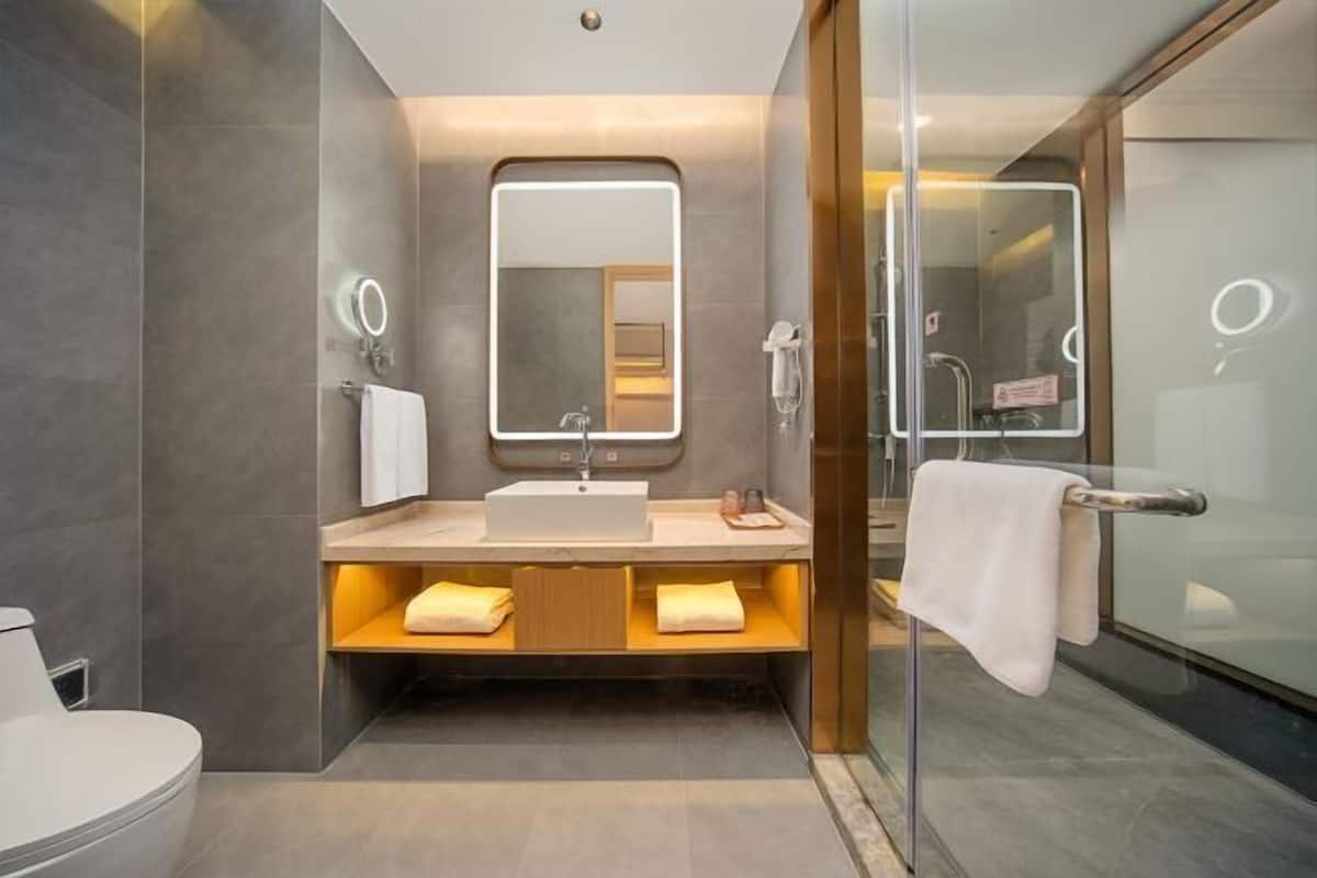 Un baño moderno con cabina de ducha de vidrio, lavamanos con espejo y un perchero para toallas.
