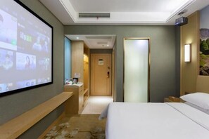 A hotel room with a bed, a desk, a projector screen displaying a video, a door, and a wall-mounted light fixture. - Vienna Hotel (Ji'an County Yanjingfu) (Ji'an County)
