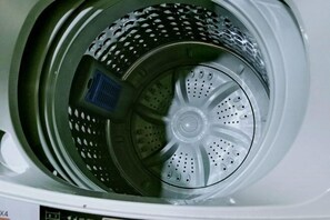 A front view of a washing machine with a transparent door, revealing the drum and internal components. - Yi Xiao Ting Hotel (Enshishi)