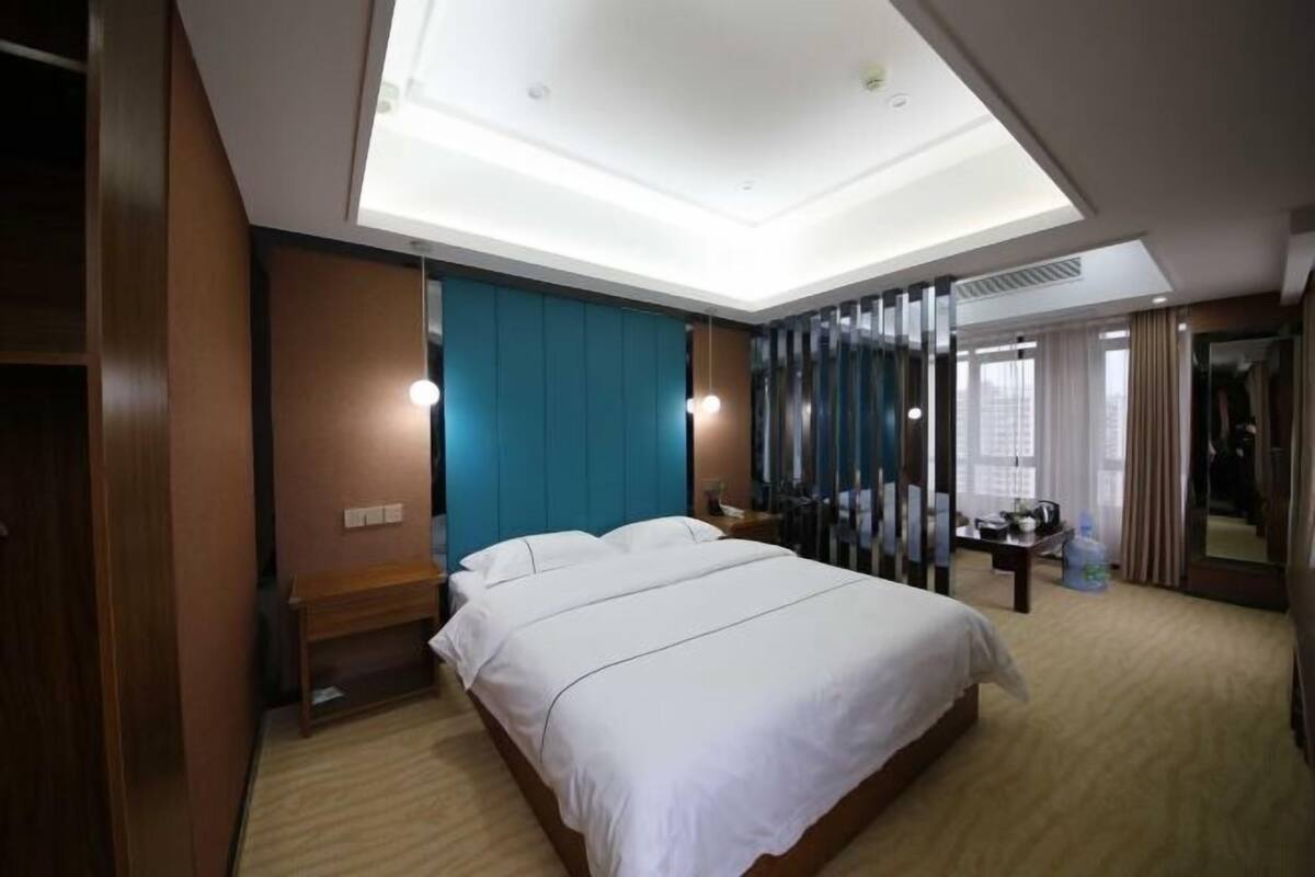 Habitación de hotel con una cama grande, un escritorio, un espejo y vistas a la ciudad.