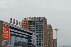 A modern building with multiple signs, including one for a hotel and another for a business. - Yi Xiao Ting Hotel (Enshishi)