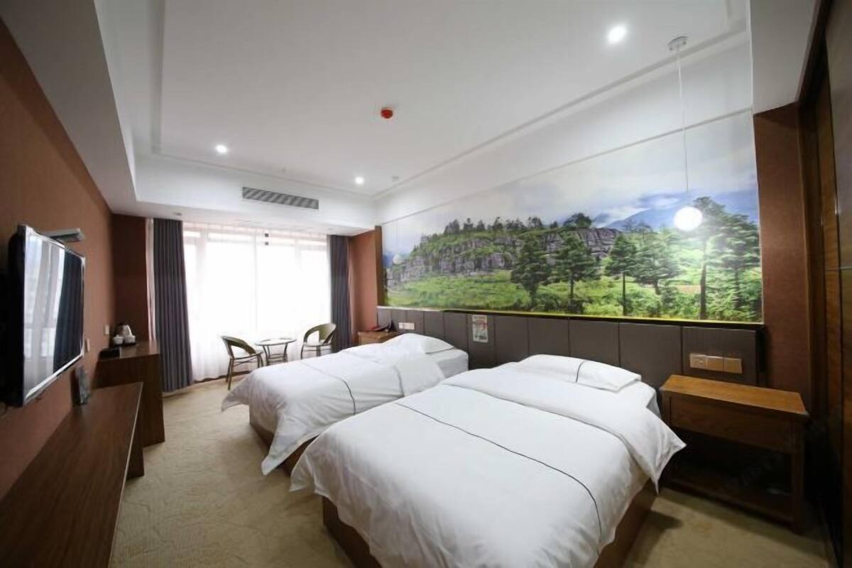 Una habitación de hotel con dos camas, televisión, escritorio y ventana con vistas panorámicas.