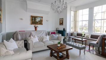 A spacious living room with a white sofa, a wooden coffee table, and a chandelier.