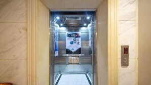 An elevator with a marble wall, a digital display showing the number 2, and a poster advertising a product. - Lvxingzhe Manbu Theme Hotel (Zhangjiajie)