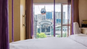 A hotel room with a large bed, a view of a cityscape, and a cable car in the background. - Lvxingzhe Manbu Theme Hotel (Zhangjiajie)