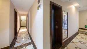A hotel hallway with a marble floor, a clock, and a door with a mirror. - Lvxingzhe Manbu Theme Hotel (Zhangjiajie)