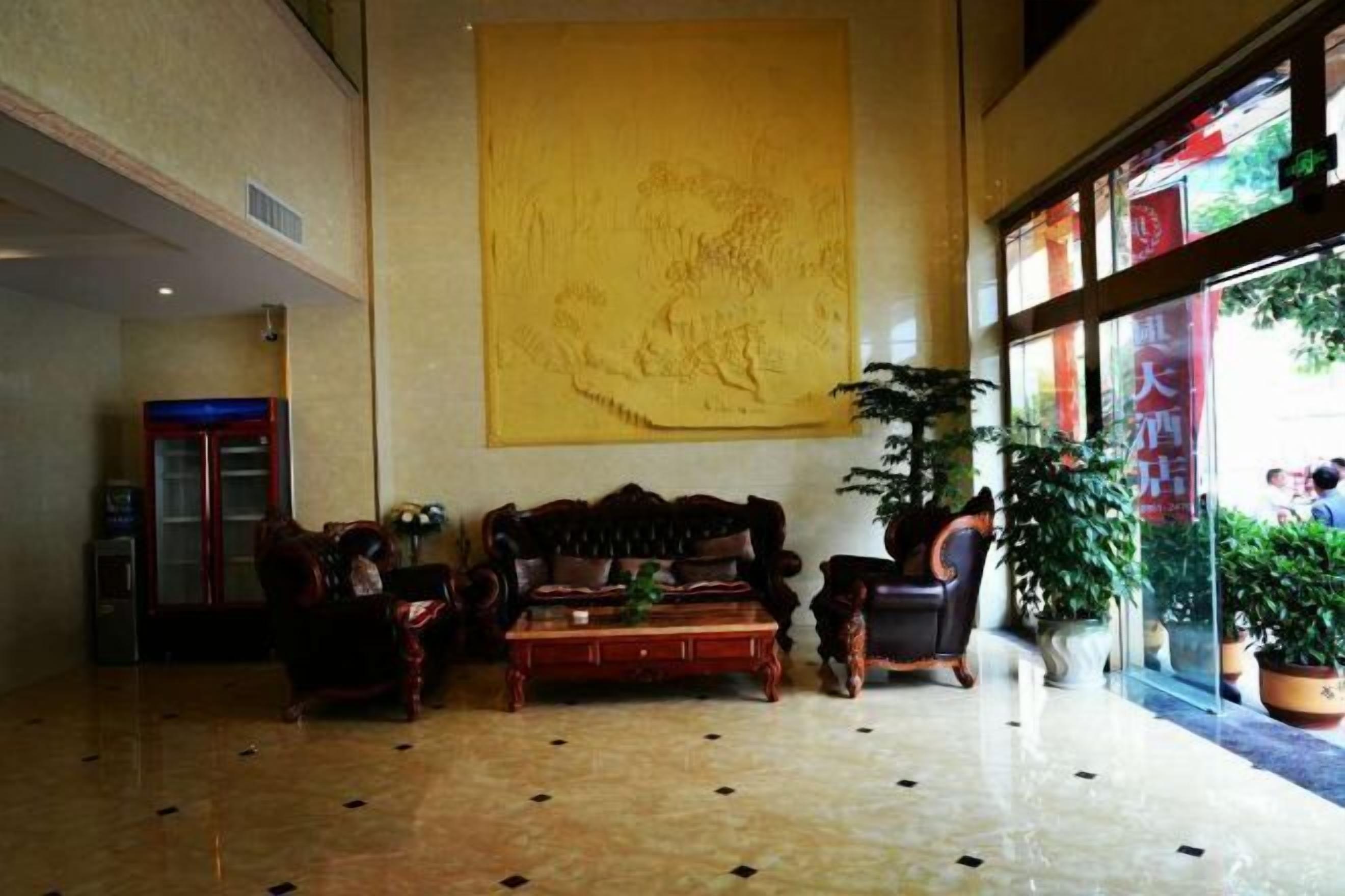 A lobby with a large yellow artwork, a sofa, a coffee table, and potted plants.