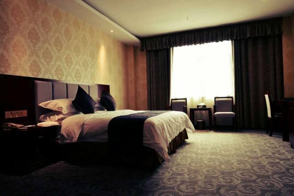 A hotel room with a bed, nightstands, a desk, and a chair.