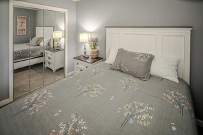 Une chambre à coucher avec un lit, des tables de chevet, un miroir et une commode.