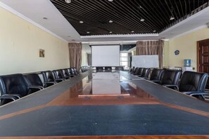 A conference room with a long table, chairs, a projector screen, and a whiteboard.