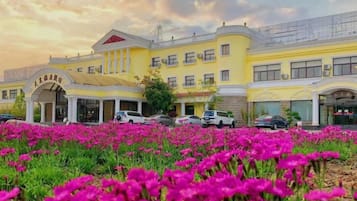 Un hotel con fachada amarilla, numerosas ventanas y un acceso cubierto.