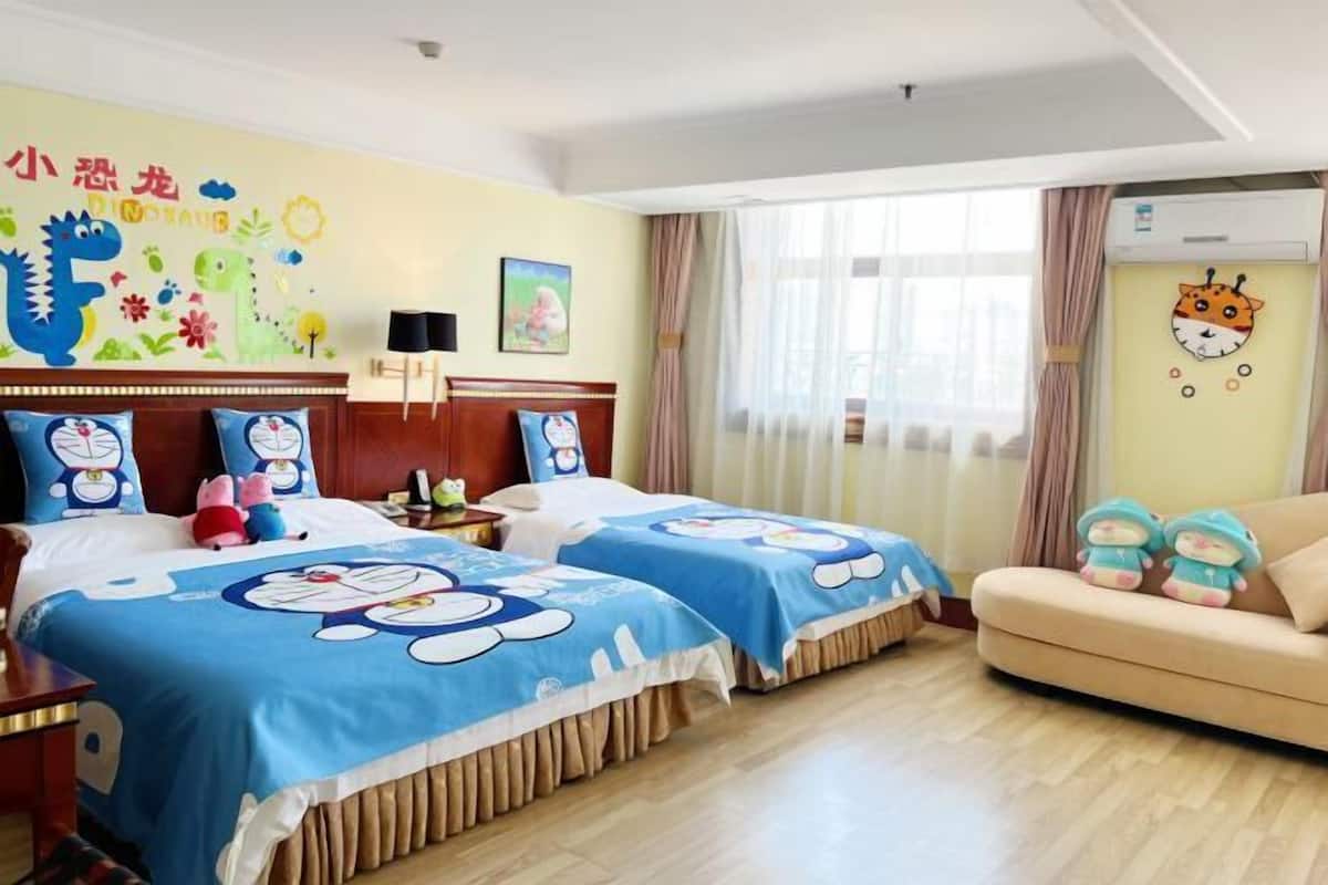 A hotel room with two beds, a sofa, a window with curtains, and a wall decoration.