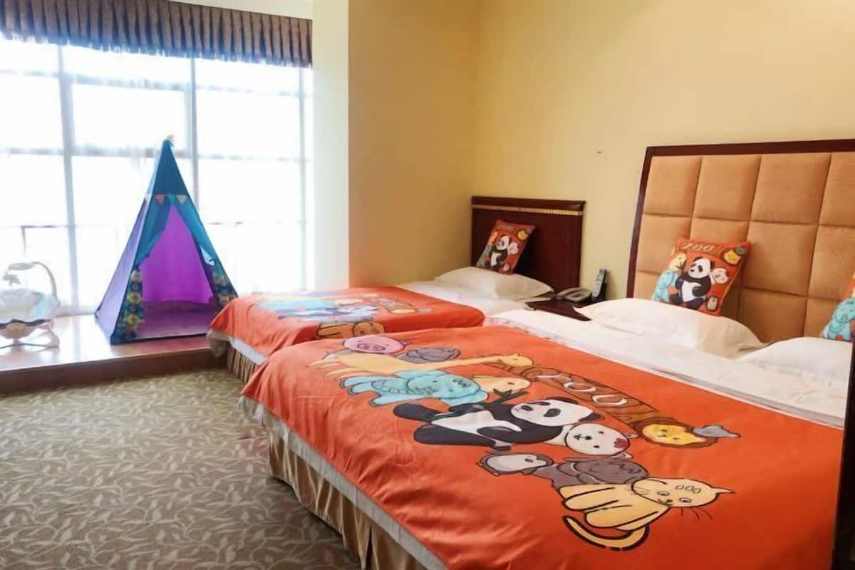A hotel room with two beds, a tent, and a window with blinds.