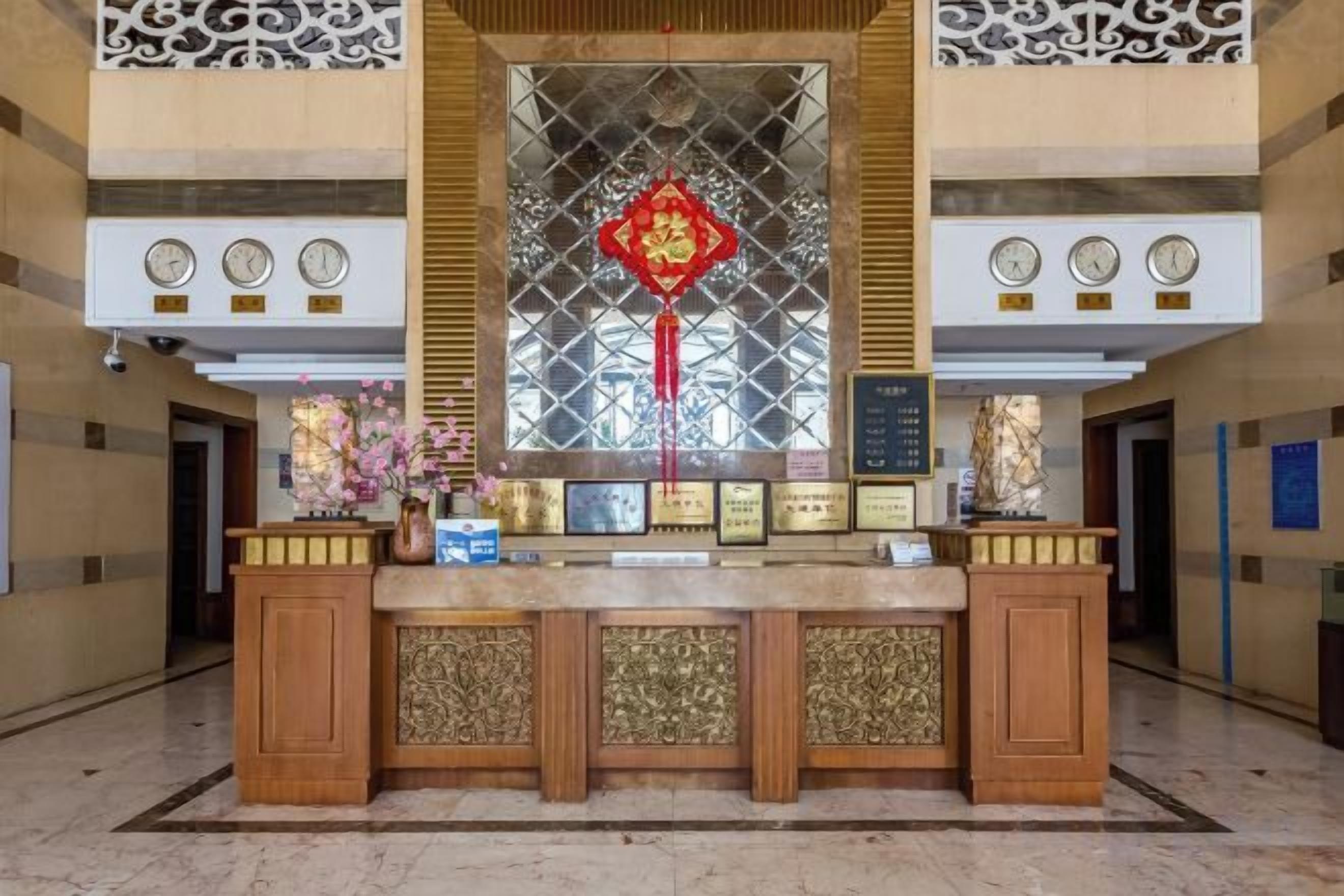 Un mostrador de recepción con un ventanal decorativo, relojes y premios enmarcados.