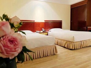 Een hotelkamer met twee bedden, een houten vloer en een groot raam.