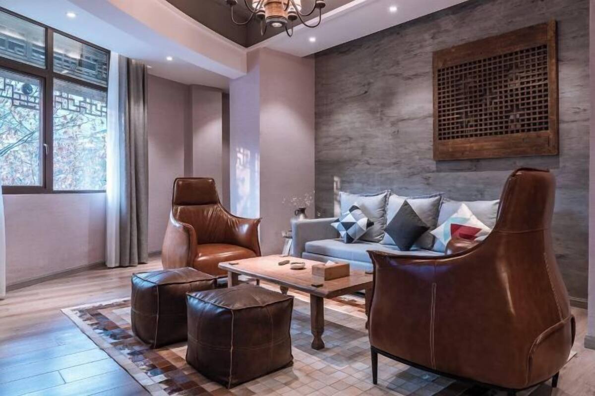 Un salon moderne avec des meubles en cuir, une table basse en bois et un canapé gris agrémenté de coussins à motifs.