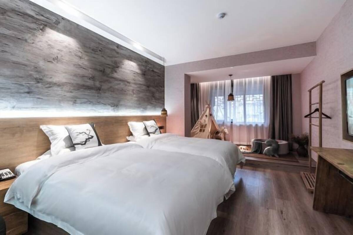 Une chambre à coucher moderne avec un grand lit, une tête de lit en bois, un fauteuil suspendu et une petite table.