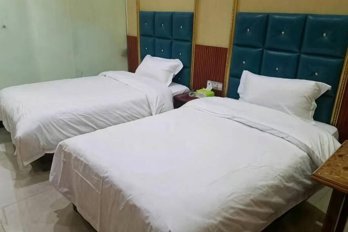 A hotel room with two beds, a wooden nightstand, and a mirror.