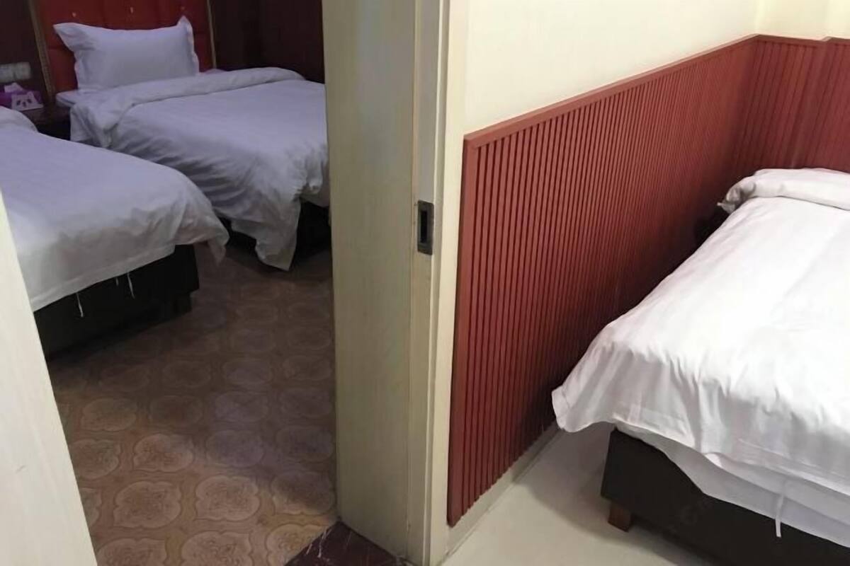 A hotel room with two beds, a red headboard, and a patterned floor.