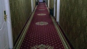 A long, narrow hallway with a red carpet and ornate patterns, leading to a door at the end. - Jinxin Hotel (Hengyang County)