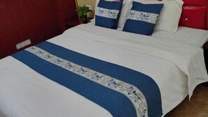 A bed with a red headboard, white bedding, and blue and white patterned pillows. - Jinxin Hotel (Hengyang County)