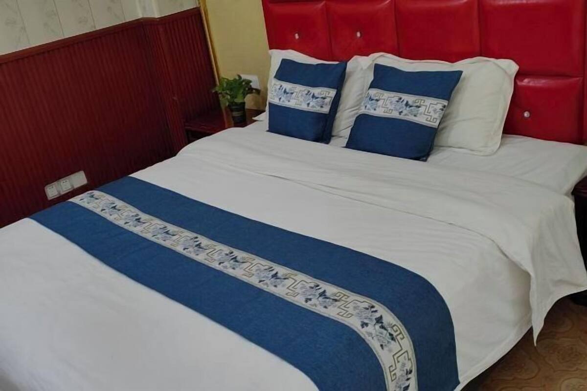 A bed with a red headboard, white bedding, and blue and white patterned pillows.