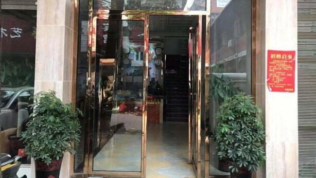 A hotel entrance with a glass door, potted plants, and a staircase leading inside. - Jinxin Hotel (Hengyang County)