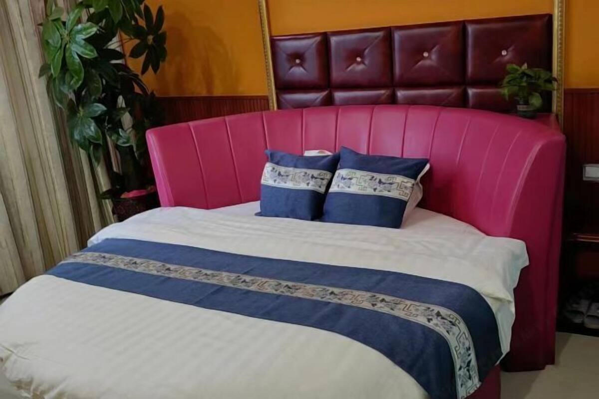 A bed with a red headboard, two pillows, and a blue and white bedspread.