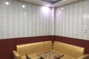 A corner room with a red wall, a gold-colored sofa, and a patterned table. - Jinxin Hotel (Hengyang County)