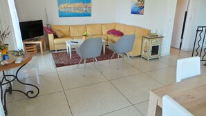 Una sala de estar con un sofá, dos sillones, una mesita de centro, un televisor y un mueble bajo.