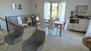 Un comedor con una mesa, sillas, una escalera y una estantería.