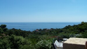 Vista costera con un área de patio que tiene una mesa y sillas, con vista al mar.