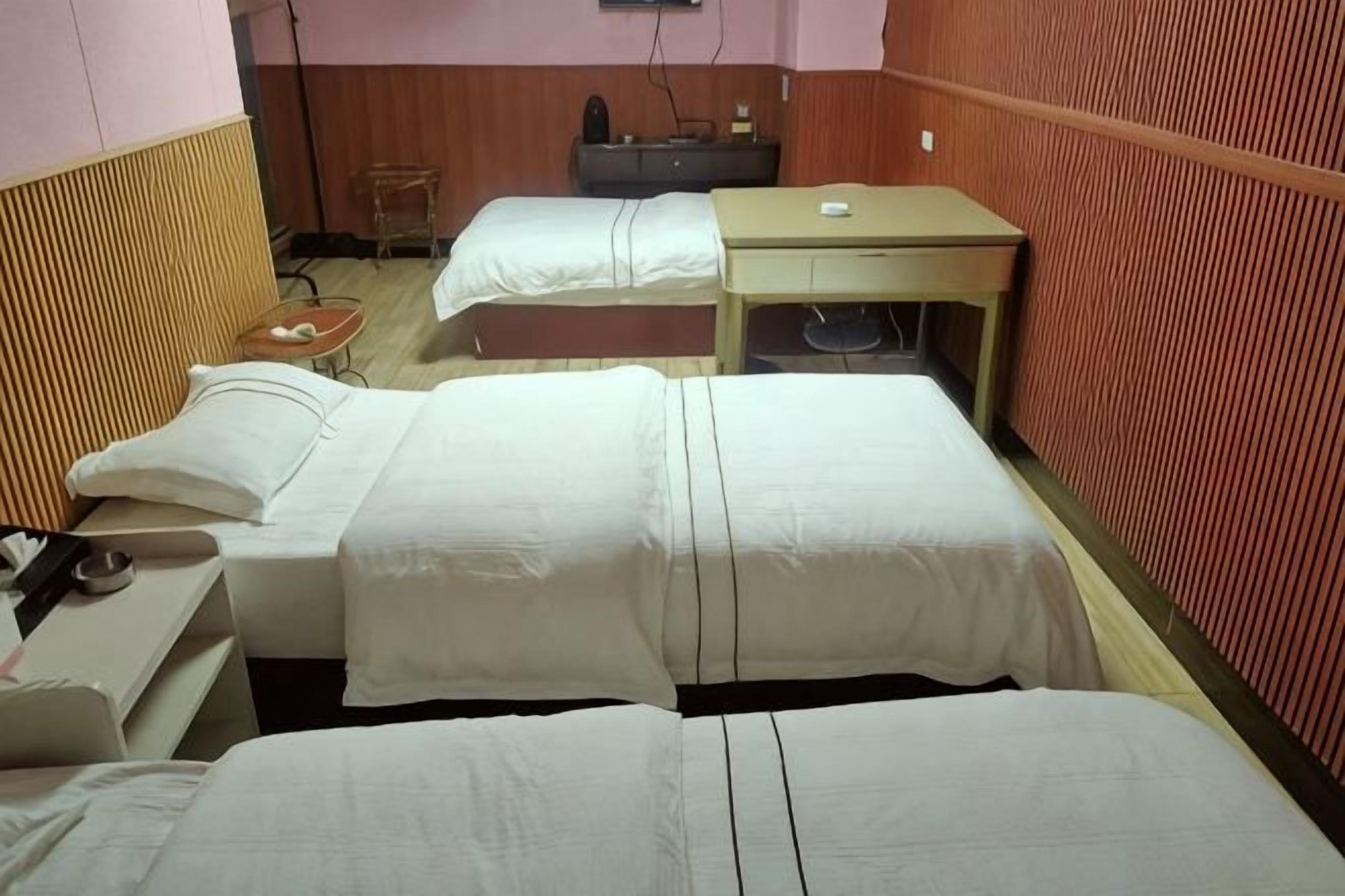 A hotel room with two beds, a desk, and a chair.