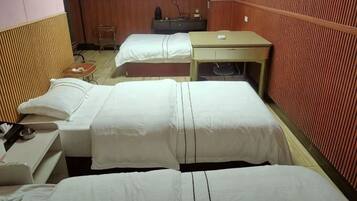 A hotel room with two beds, a desk, and a chair.