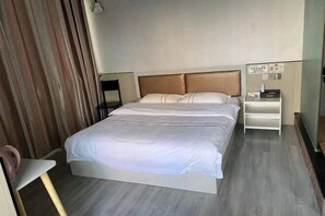 Quarto de hotel com cama, mesa de cabeceira, cadeira e cortina.