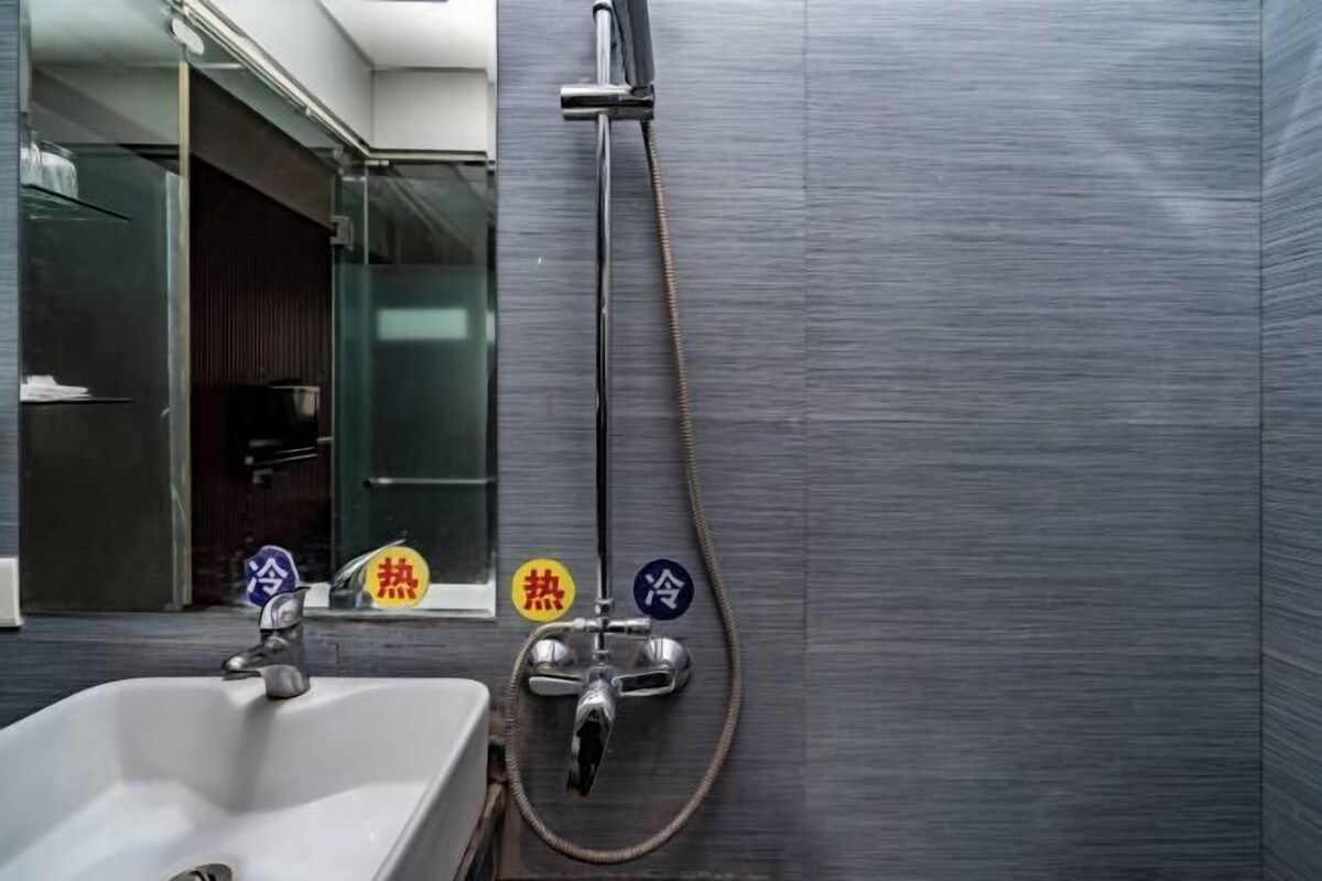 Une salle de bain équipée d’un lavabo, d’une douche avec réglage de la température et d’une paroi de douche en verre.