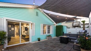 A turquoise house with a covered patio, a sliding glass door entrance, and a barbecue area. - Cottage on the Rocks - 3 Bedrooms - Walk to Beach - Outdoor Seating - Pet Friendly (North Myrtle Beach)