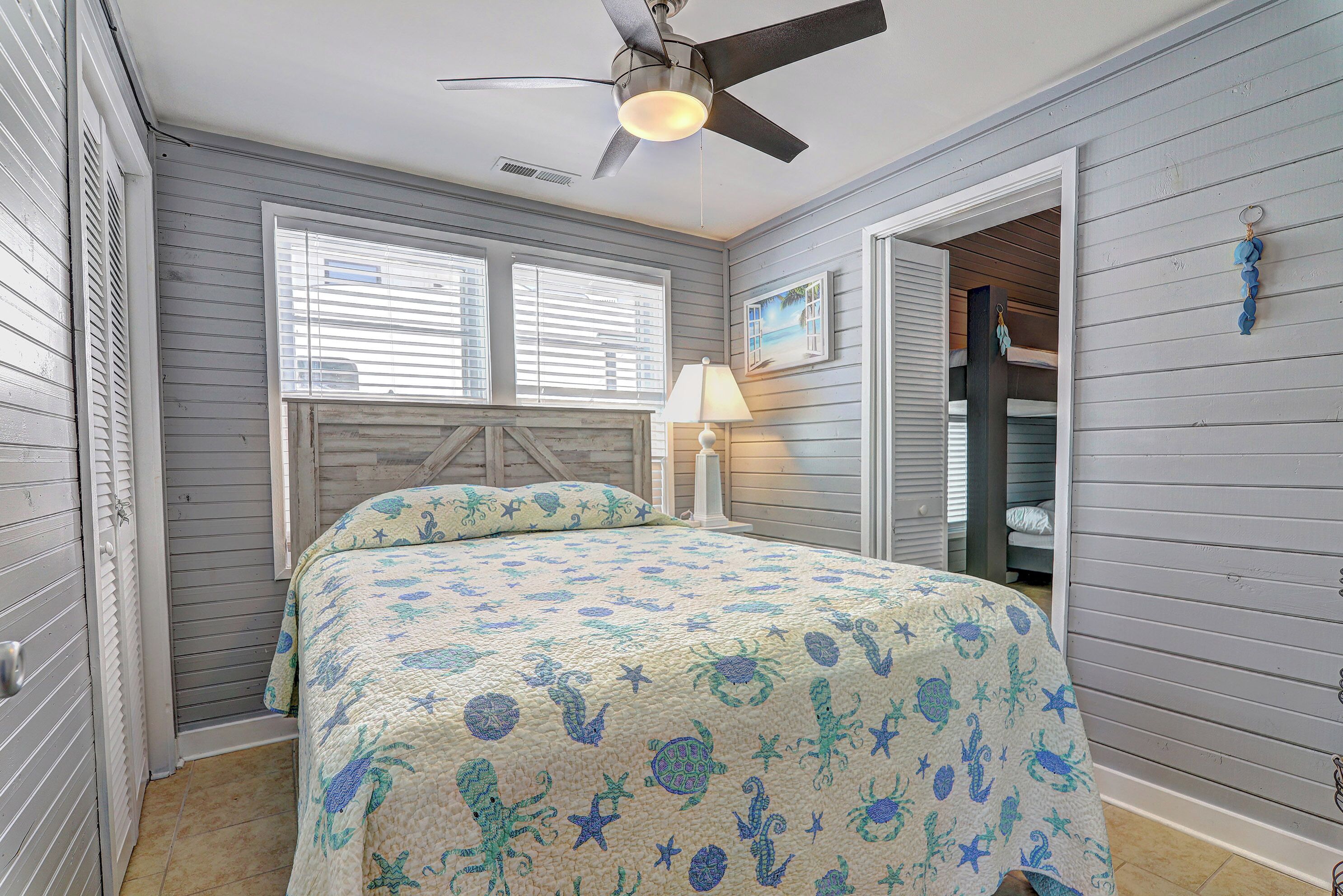 A bedroom with a bed, a ceiling fan, and a window with blinds.