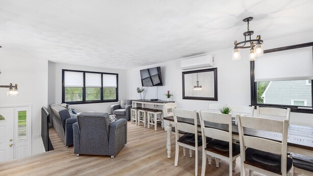 Ein modernes Wohnzimmer mit Kamin, einer Essecke mit Holzkästen und einem großen Fenster, das natürliches Licht hereinlässt.